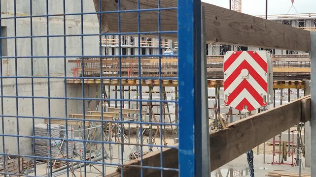 Tower crane hook block with chains moving past an outrigger platform shot from a high floor level in slow motion.