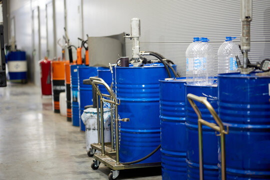 nside a busy automotive service center, blue barrels of oil stand in an orderly manner. The scene depicts the essential supplies needed for vehicle maintenance, ensuring a professional atmosphere.