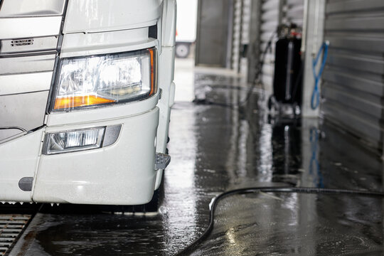 This image features a white truck parked at a car wash specifically designed for larger vehicles. The facility showcases ample space and facilities catering to suvs and trucks.