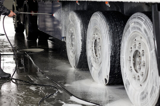 A professional cleaning of truck wheels and rims takes place at a specialty wash station. Foam and water are used to ensure a sparkling finish, showcasing the meticulous care for heavy-duty vehicles.