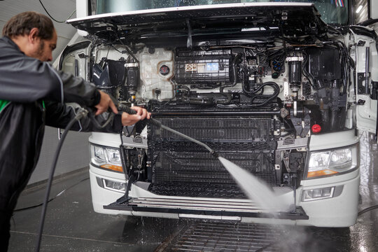 An expert cleaner meticulously washes a white truck using a contactless washer in a modern, spacious car wash facility. The clean environment highlights efficiency and attention to detail.