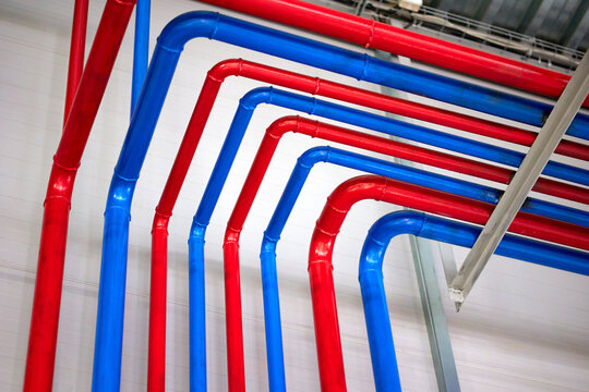 A vibrant and colorful network of bright blue and red heating or water supply pipes crisscrossing through urban infrastructure, showcasing modern engineering and design in a city setting.