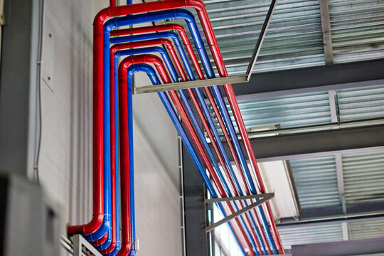 A vibrant display of blue and red pipes intertwined, symbolizing water supply and heating systems. Ideal for plumbing, construction, or infrastructure-related projects in stock photography.