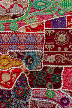 Traditional indian patchwork tapestry background. Close up of handmade vintage indian patchwork carpet featuring vibrant ethnic patterns detailed floral embroidery and beadwork textures, India