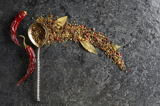 Mix of organic dried spices on a black stone background.