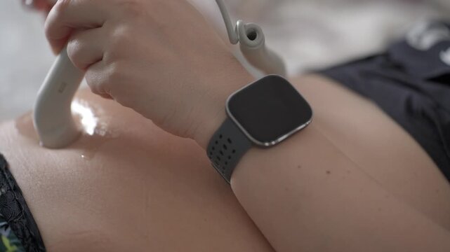 A close-up of a pregnant woman, listening to the sound of her baby's heartbeat through a pocket-sized fetal doppler device, to monitor the baby's heart rate.