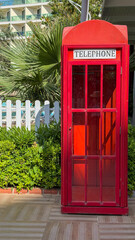 Obraz premium Classic Red British Telephone Booth In Tropical Luxury Resort With Palm Trees And Summer Vacation Atmosphere.