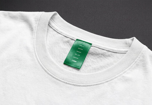 White cotton t-shirt collar mockup with a green fabric clothing label tag on a dark gray background