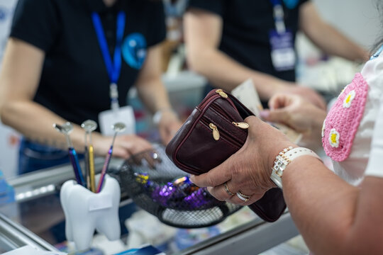 Customer Paying at Dental Clinic Reception. Close-up of a customer holding a wallet while paying for dental clinic products or services at the reception counter.