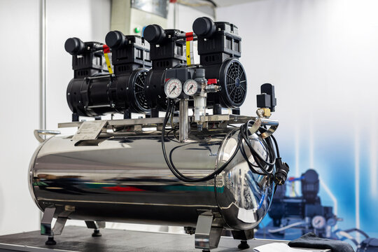Industrial Air Compressor in Dental Clinic. Close-up of a stainless steel air compressor with pressure gauges and motors used for dental clinic equipment.