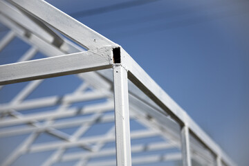 The metal frame made of profile tubing is painted white. The white metal frame stands against a blue sky. © PhotoFed