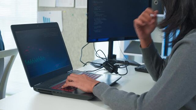 Two focused software engineers collaborating on code in modern office, professional developers discussing project on laptop and computer screen