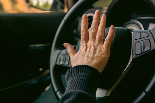 Female driver hand honking on steering wheel close-up in car interior emphasizing safety and control while driving