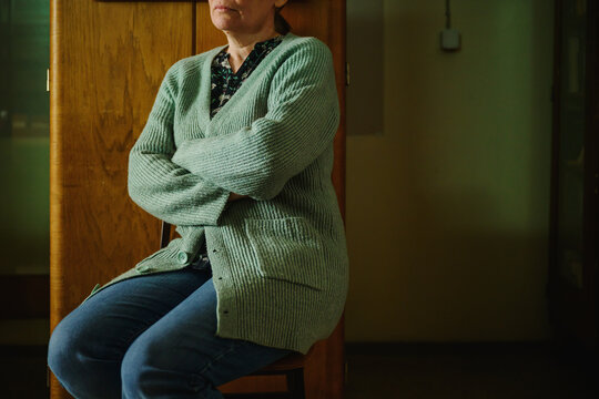 Portrait of mature adult female librarian sitting in a wooden chair in old office library