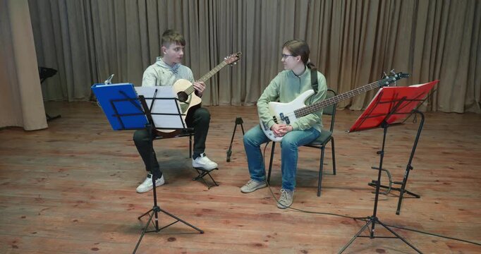 Boy and Girl Practice Playing Music on Stage. Kids Play Guitar and Bass Guitar. 4K 10-bit