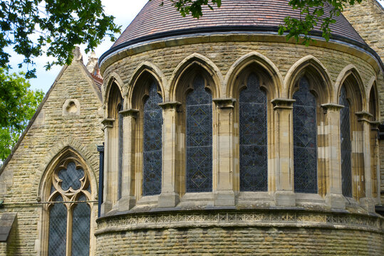 Gothic revival church apse featuring arched stained glass windows and stone architecture details.