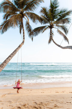 Girl swinging between palm trees on a tropical beach in Sri Lanka