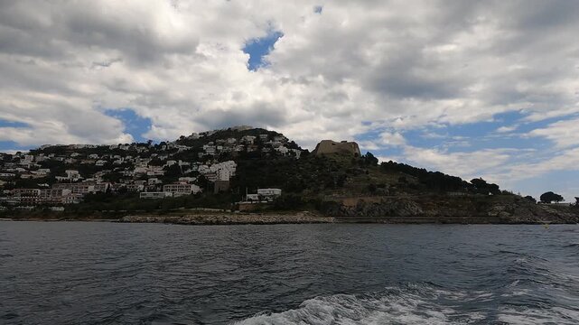 Video filmed from a boat showing views of La Trinidad Castle, located at the tip of the headland that encloses the inner bay of the Gulf of Roses, in the province of Girona, Catalonia, Spain