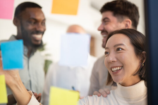 Diverse business team collaborating with sticky notes on glass