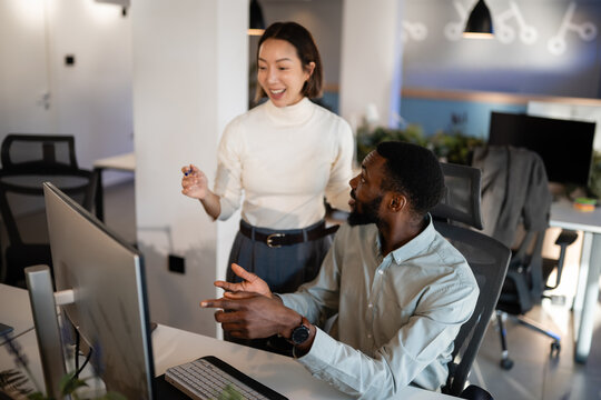 Diverse colleagues collaborating on computer in modern office