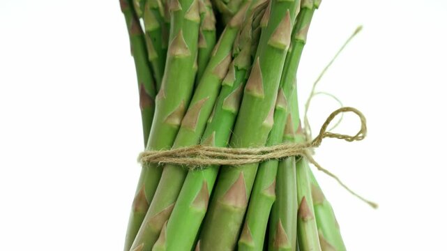 Healthy fresh asparagus edible shoots zooming out slowly revealing green sparrowgrass stalks isolated on white background