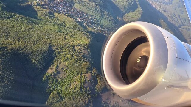 Jet engine of an airplane with a scenic view of green mountains high in the sky