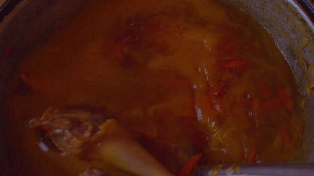 Close-up shot of tender chicken meat chunks and chopped vegetables simmering in a soup broth.Procees of homemade chicken soup preparation.Top view.