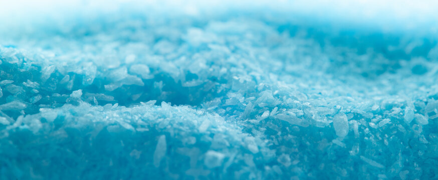 Close-up view of blue salt crystals on a flat surface in a bright light