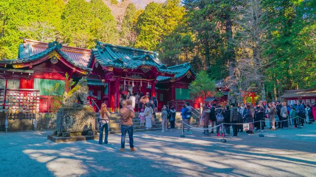 HAKONE, KANAGAWA, JAPAN. DECEMBER 14, 2025. TIMELAPSE. Tourists and local visitors queueing in front of the main red pavilions of the historic Hakone Jinja Shrine.