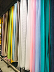 Fototapeta na wymiar A variety of colorful curtains in different hues hanging inside a store for decoration