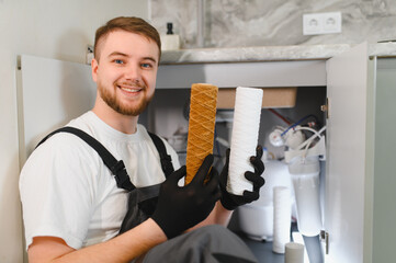 Plumber replacing reverse osmosis water filter cartridge