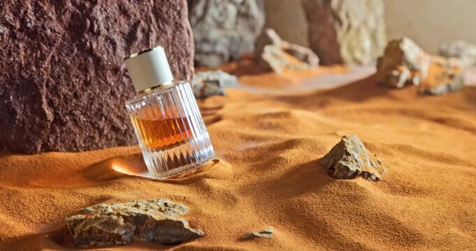 Unique amber perfumes in translucent glass bottle on sand.
