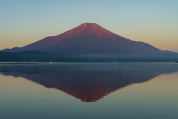 Fototapeta premium Stunning Aka-Fuji (Red Mount Fuji) with a perfect reflection on the mirror-like surface of Lake Yamanaka in September, Japan.