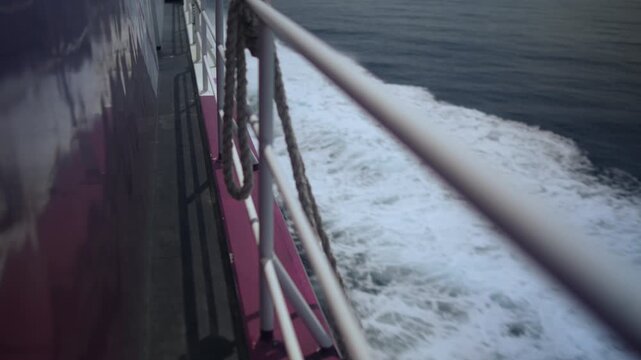 Side deck view from a passenger ferry overlooking ocean waves and the distant horizon during a calm summer voyage