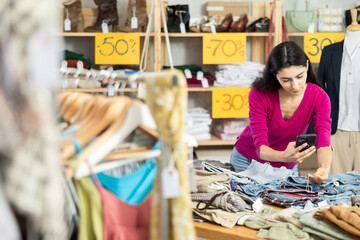 Obraz premium Young female customer scans QR code on pants or shorts label, activates discount code, and registers purchase in clients personal account, verifies quality certificate..