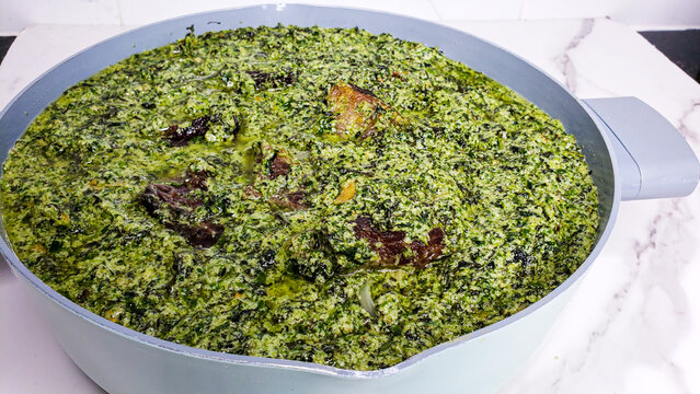 Traditional Cameroonian Ndole soup made with bitter leaves and peanuts in white pot