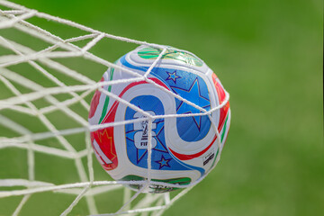 Naklejka premium Calgary, AB, Canada. May 23, 2026. Official FIFA World Cup 2026 match ball hitting the white goal net on a sunny green pitch.