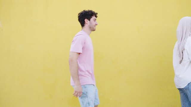Multicultural friends walking one after another in profile against a yellow wall. A diverse group of people representing unity and community
