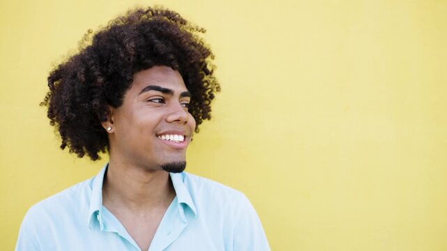 Handsome young latin man with a big curly afro hairstyle showing different happy and joyful expressions in front of a yellow background
