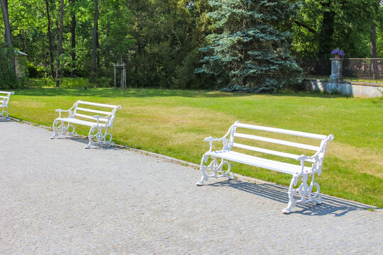 Warsaw, Poland,May 24, 2026. Two elegant white wooden benches are arranged along a quiet gravel walking path in the formal Wilanow Palace park. High quality photograph