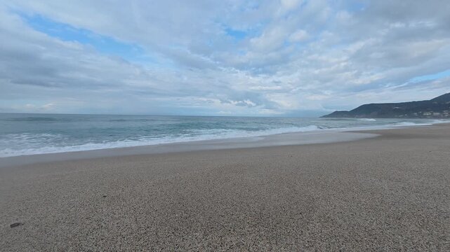 Cloudy beach waves. Waves beach cliff. sandy beach, sea foam, dramatic sky. High quality 4k footage