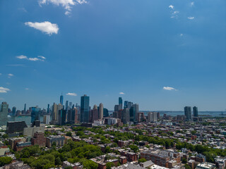 Fototapeta premium Jersey city skyline panorama showing diverse urban architecture and residential neighborhoods with the manhattan horizon visible under a bright blue summer sky