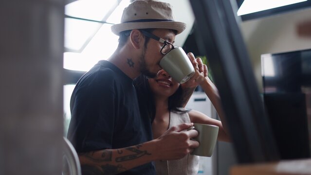 Affectionate couple sharing morning coffee at home, enjoying cozy relationship