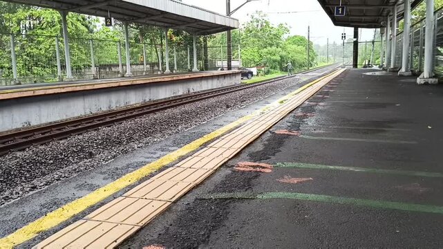 Empty railway station platform tracks next to covered passenger waiting area during daytime
