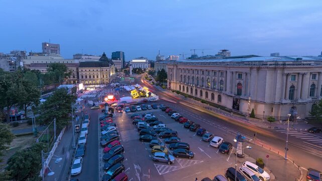 Bucharest, Romania - 01 October 2020: View of Revolution Square with parked cars, historic buildings, and the National Museum of Art under a twilight sky.