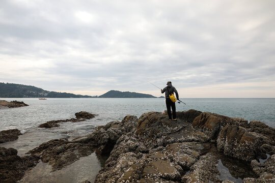 man standing on the rocks fishing