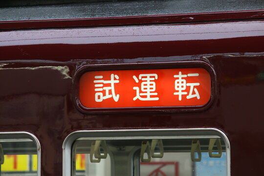 マルーン色の電車の車体に表示された赤地の試運転の方向幕
