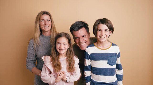 Beautiful family portrait of parents with their son and daughter smiling and having fun together during a photo session in a studio