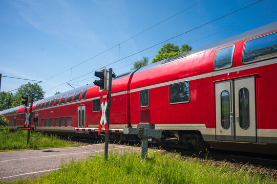 Ein Zug mit Doppelstockwagen f&auml;hrt an einem Bahn&uuml;bergang vorbei