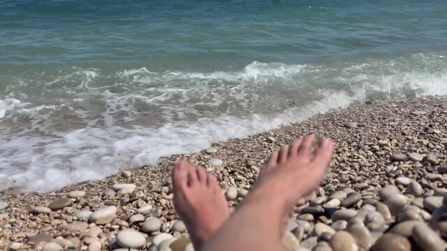 Pies desenfocados con olas rompiendo en la orilla del mar